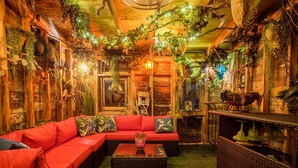 A cozy room with a red sofa, wicker coffee table, and a chandelier.