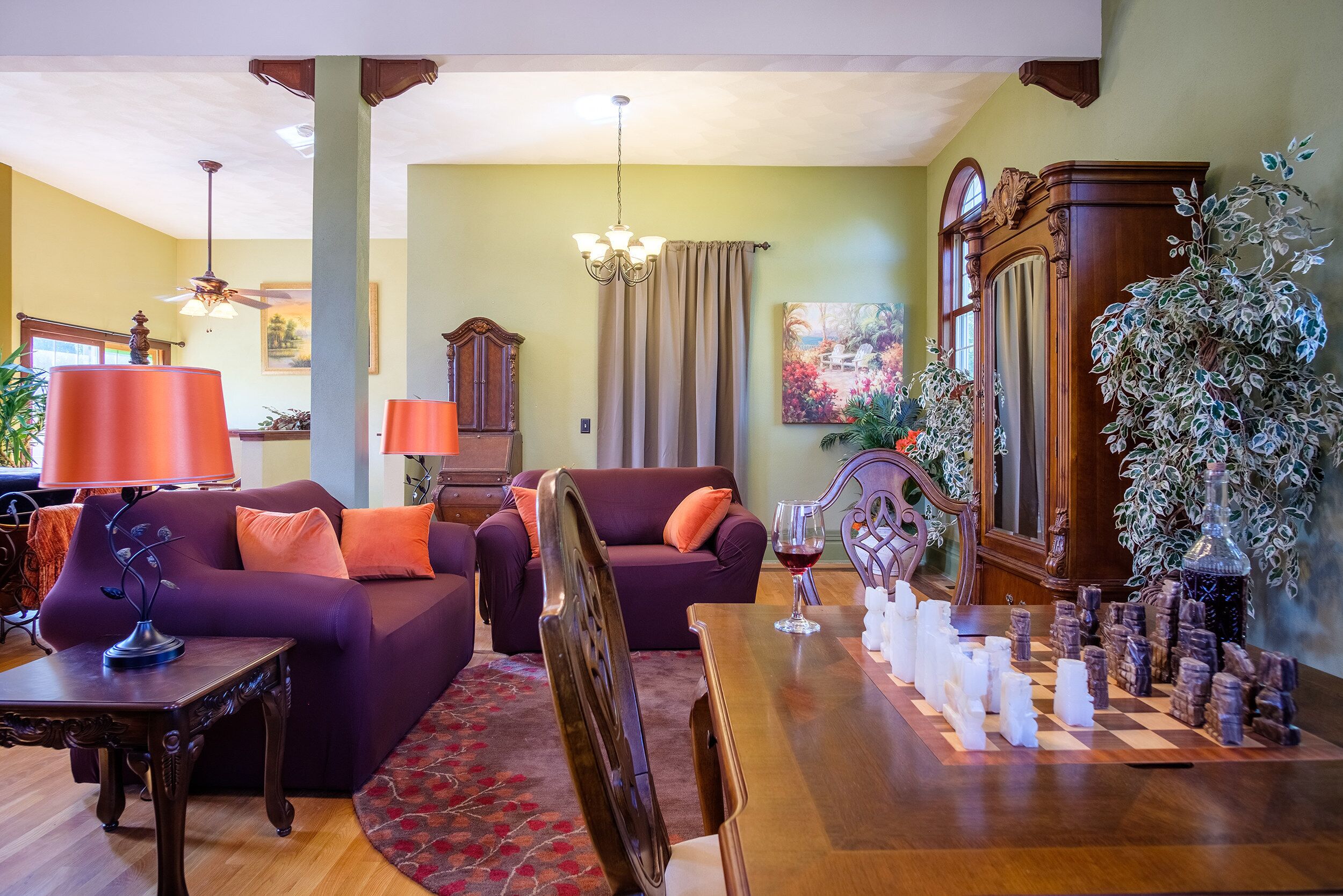 A living room with a sofa, armchair, wooden coffee table, and a chessboard.