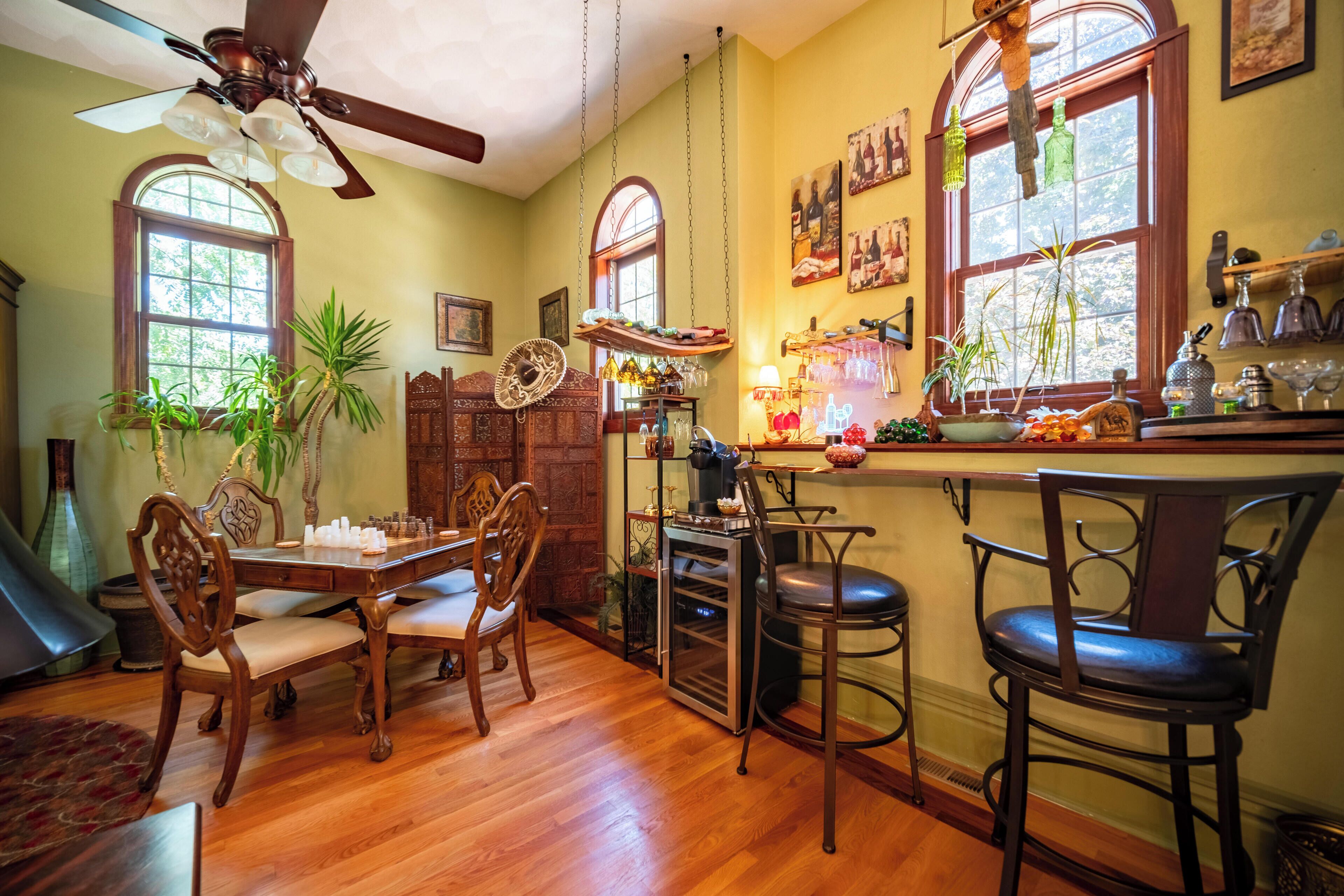 A dining area with wooden furniture, a ceiling fan, and a bar area with stools.