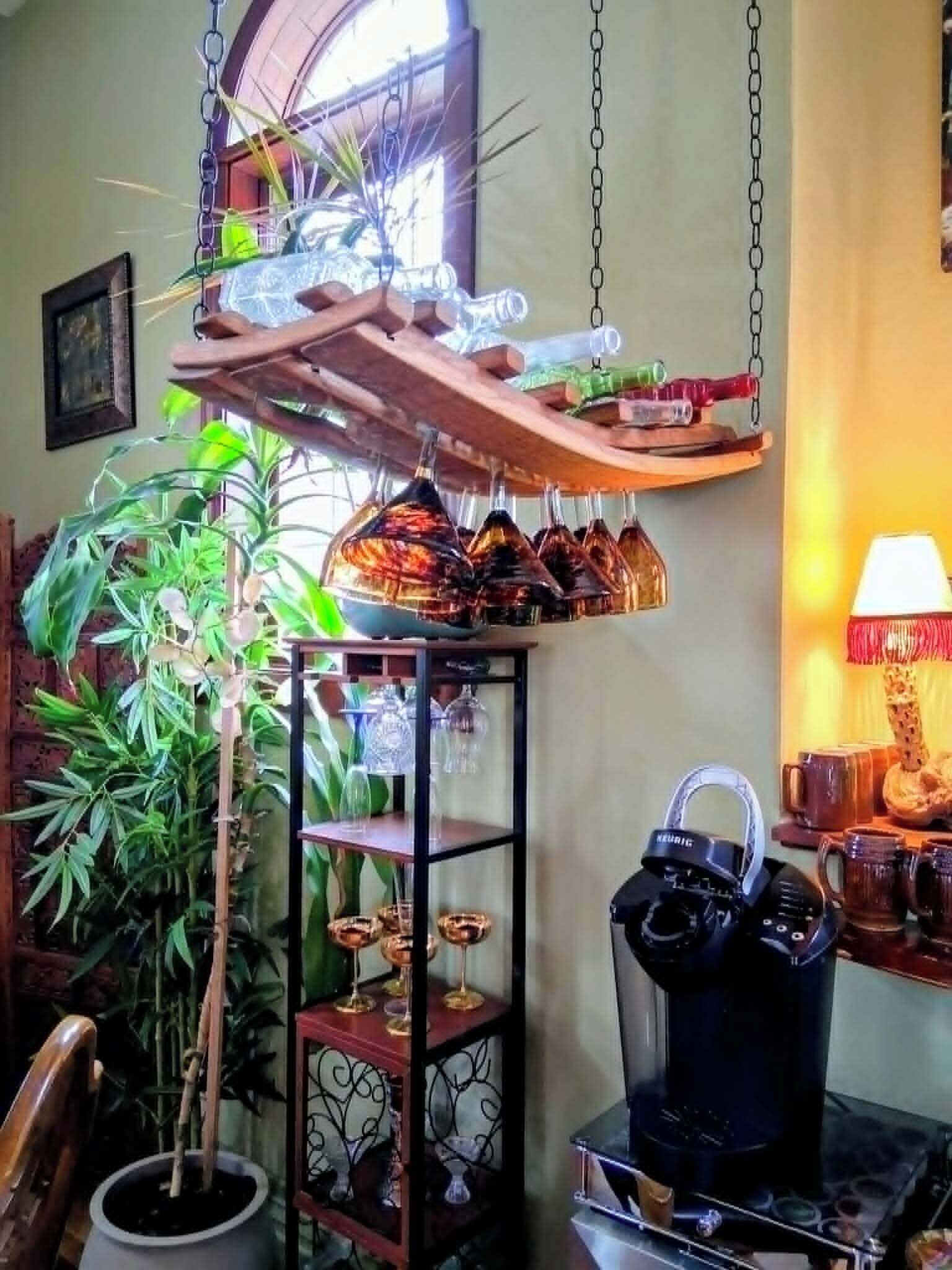A cozy room with a hanging shelf holding various glassware and a coffee maker on the table.