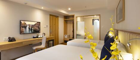 Habitación de hotel con cama, escritorio, silla, mesita de noche y espejo.