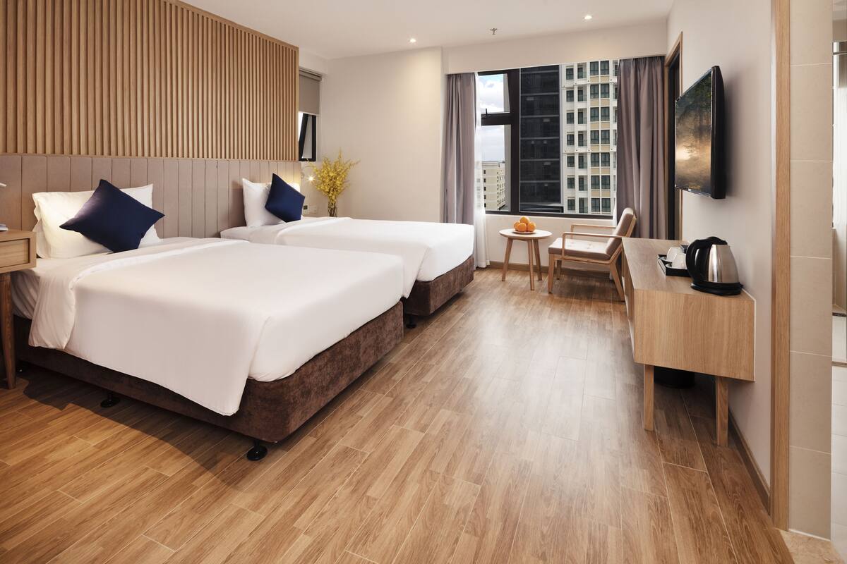 Habitació d'hotel amb dos llits, una taula, una cadira i un televisor.