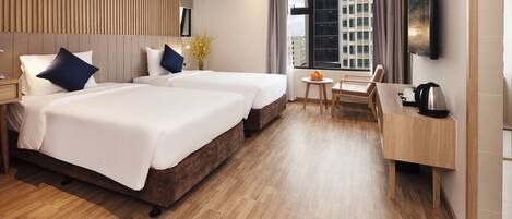 A hotel room with two beds, a desk, a chair, and a TV.