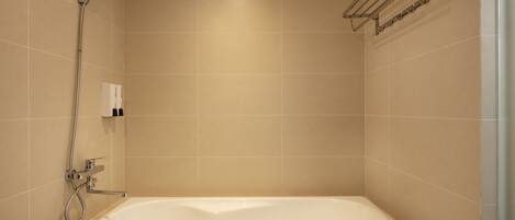 A modern bathroom with a freestanding bathtub, a handheld showerhead, and a towel rack.