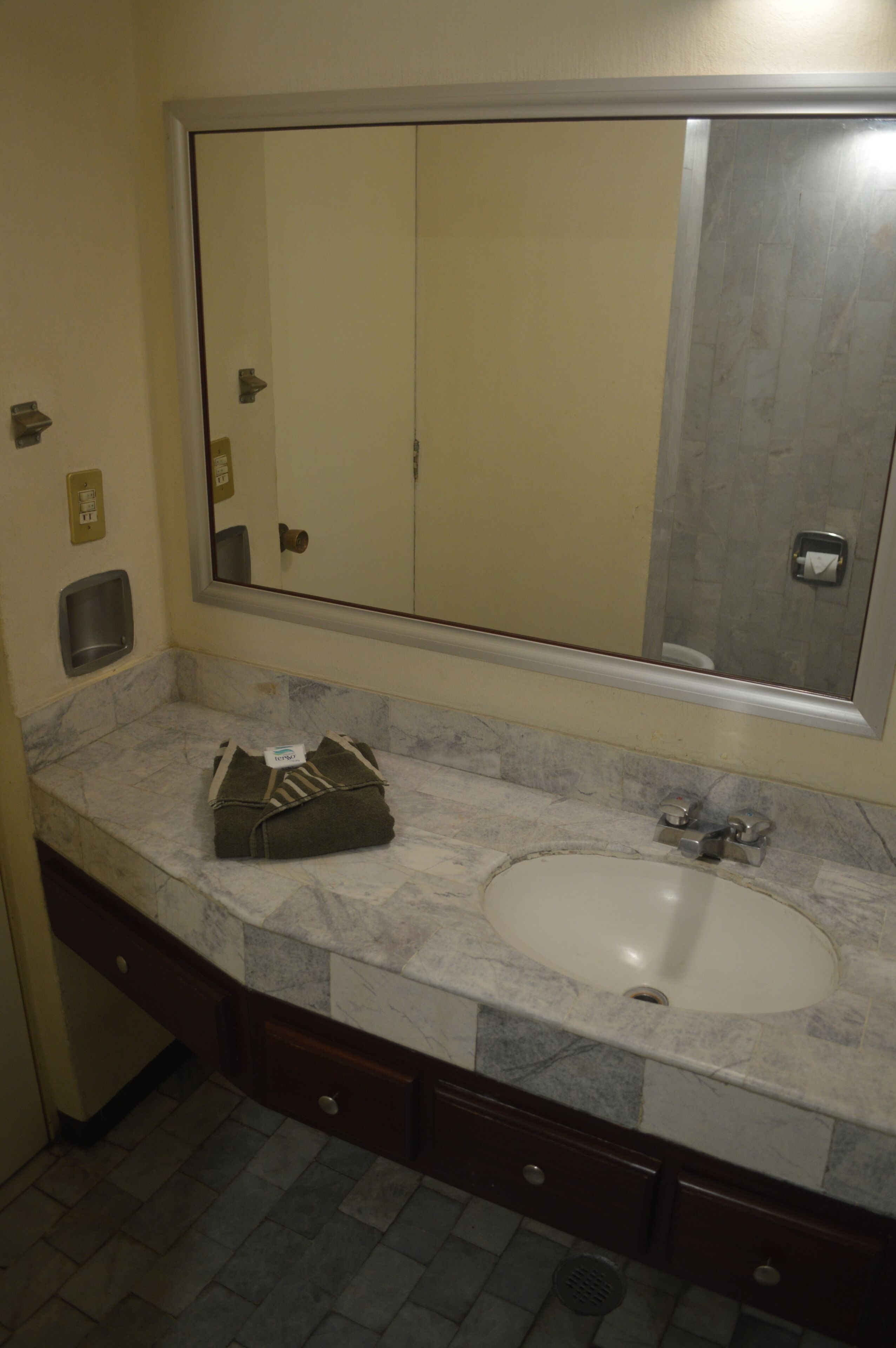 A bathroom with a marble sink, a large mirror, and a towel on the counter.
