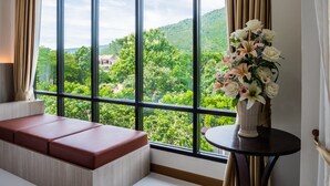 A room with a large window, a bench, and a vase of flowers. - Ozone Hotel Khao Yai (Pak Chong)
