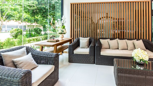 A modern living room with wicker furniture, a wooden partition, and a view of greenery outside. - Ozone Hotel Khao Yai (Pak Chong)