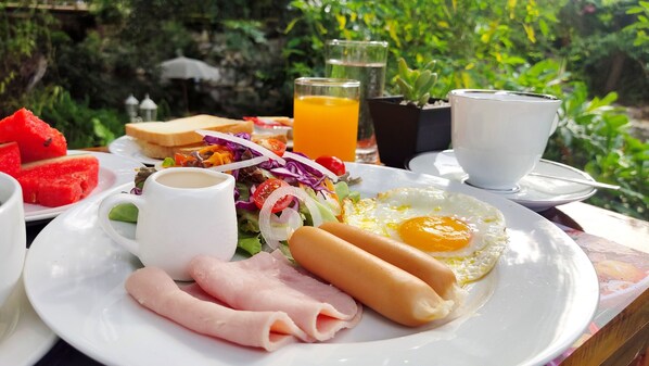 A breakfast plate with ham, eggs, and a salad, accompanied by a glass of orange juice and a cup of coffee. - Ozone Hotel Khao Yai (Pak Chong)