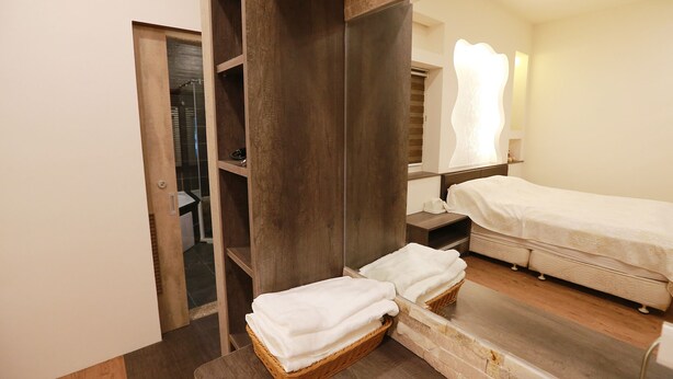 A hotel room with a large mirror, a bed, a wooden wardrobe, and a small table with a basket of towels. - Water Tail Homestay (Puli)