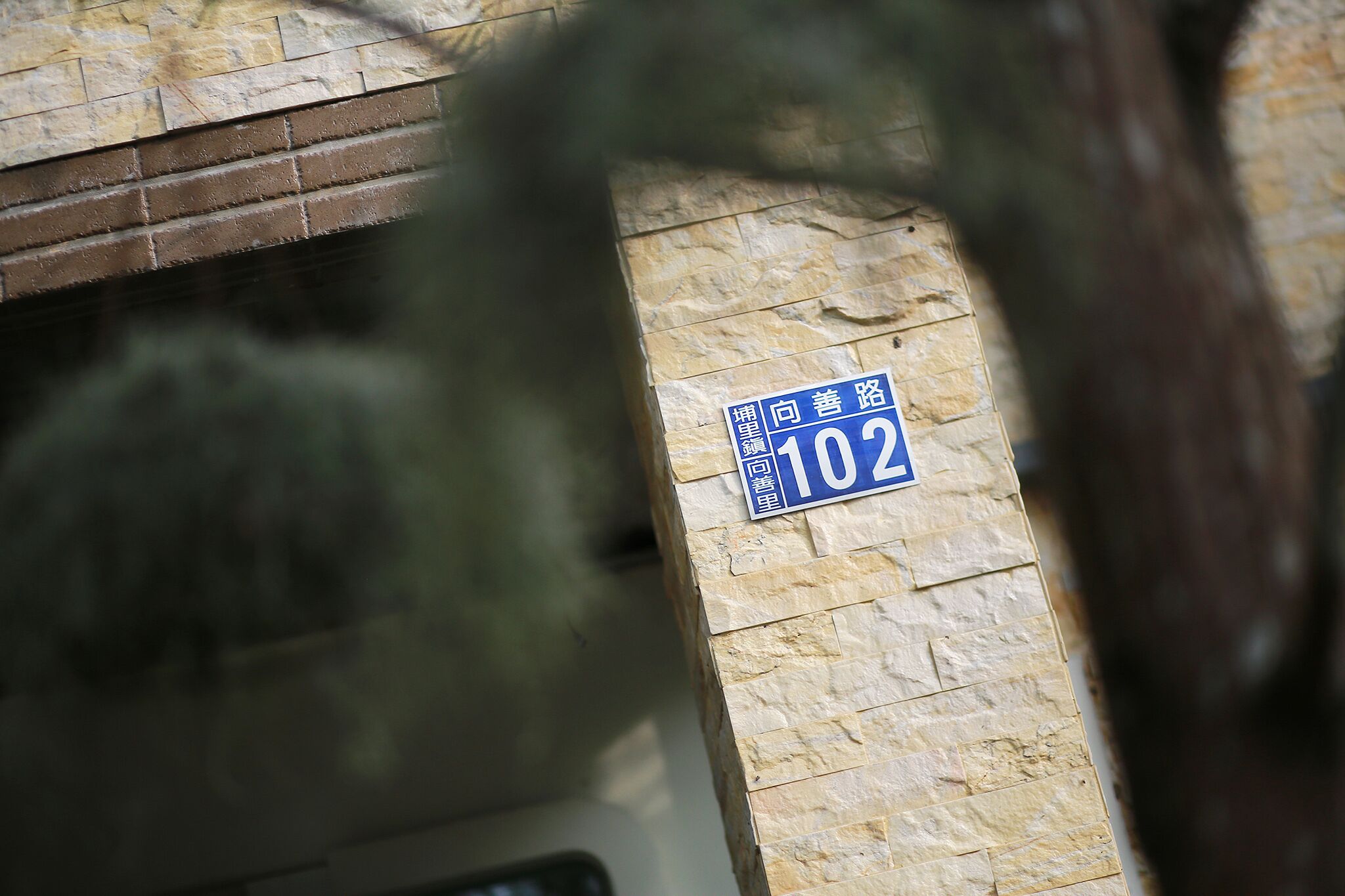 Eine Steinmauer mit einem blauen Schild, das die Nummer 102 zeigt.