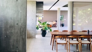 Una zona de menjador moderna amb una paret d'accent de formigó, una taula de fusta i cadires.