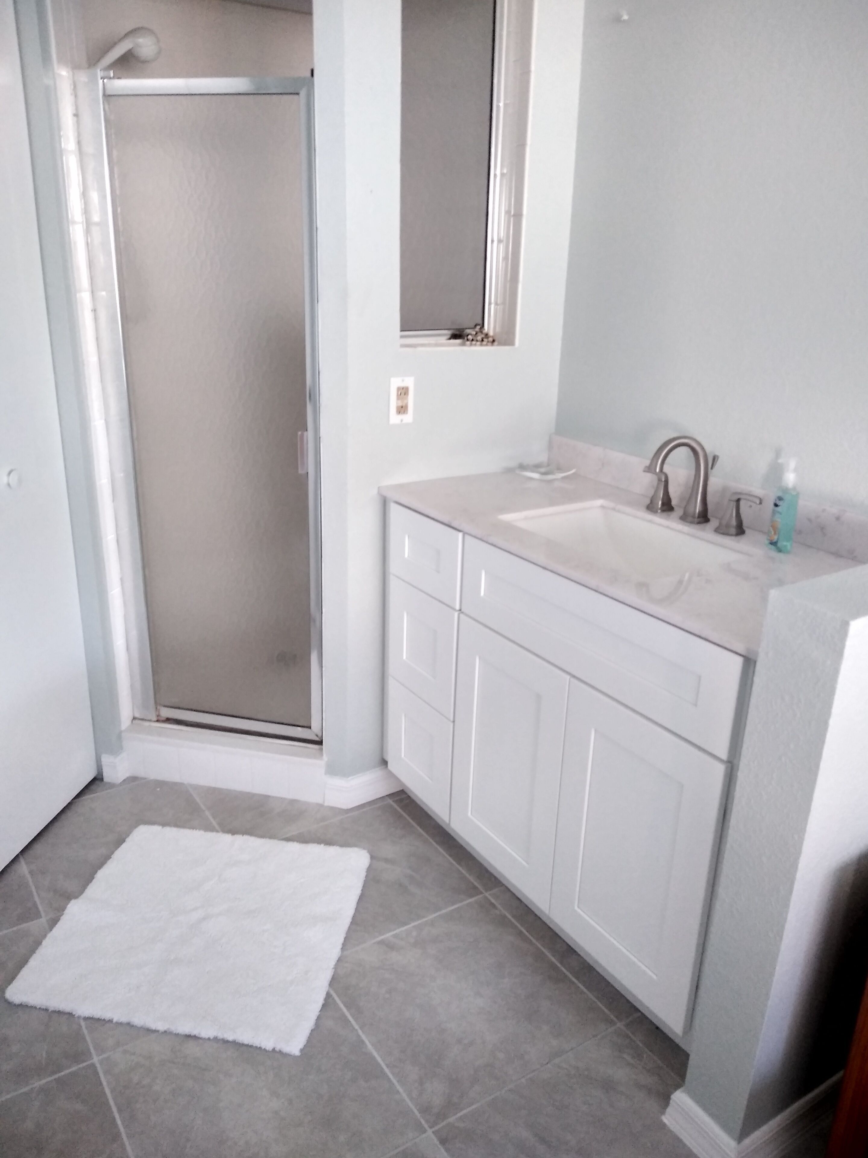 Ein Badezimmer mit Dusche, Waschbecken und Spiegel.