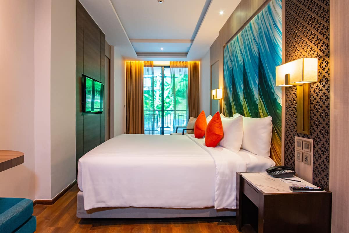 Ein Hotelzimmer mit einem großen Bett, einem Schreibtisch mit Telefon und einem an der Wand montierten Fernseher.