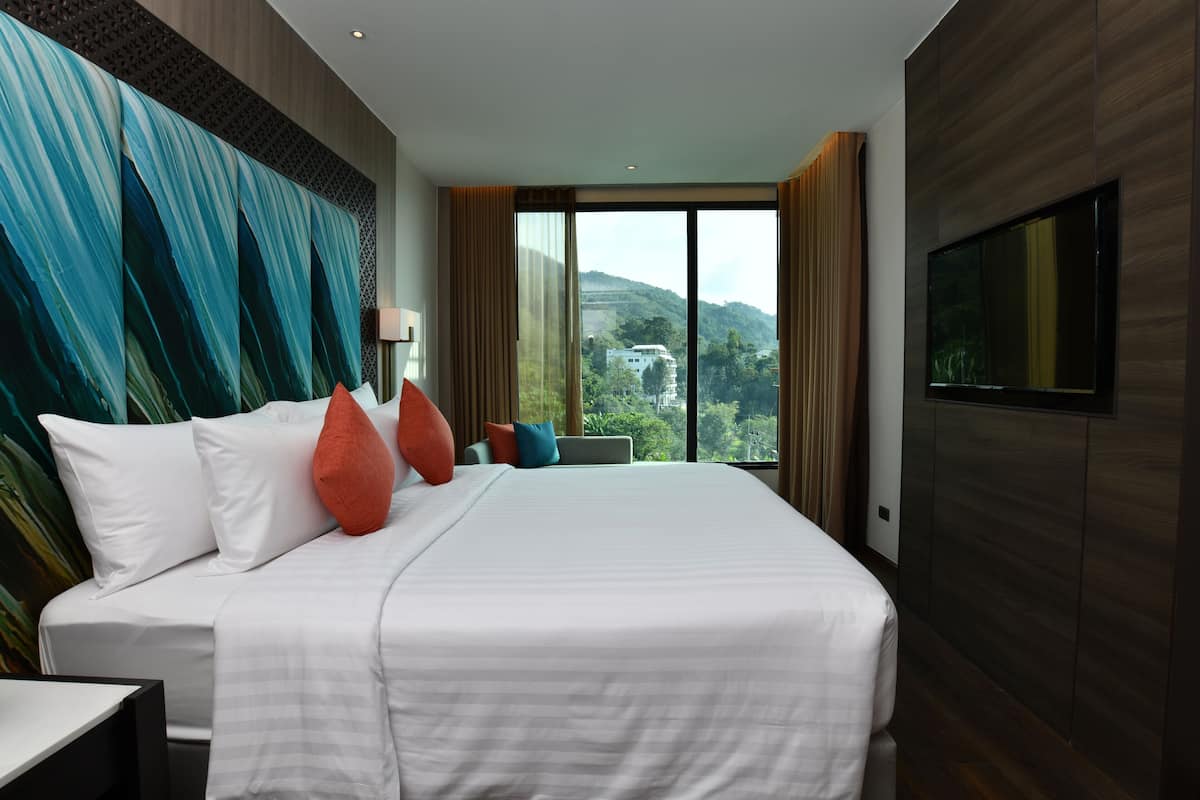 Ein Hotelzimmer mit einem großen Bett, einem Fernseher und Blick auf die Berge.
