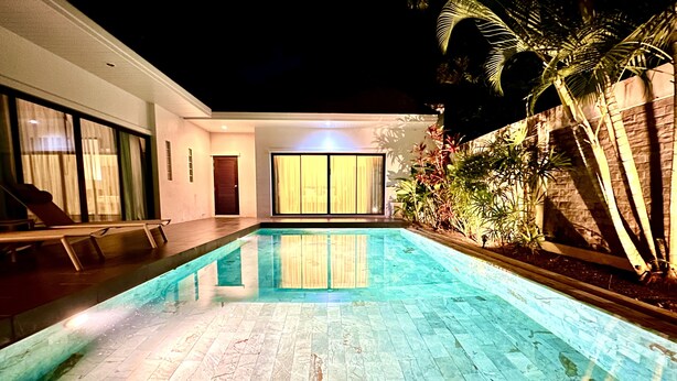 A swimming pool with a tiled deck, a door, and a window with curtains.