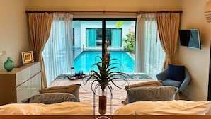 A bedroom with a bed, a TV, and a view of an outdoor swimming pool.