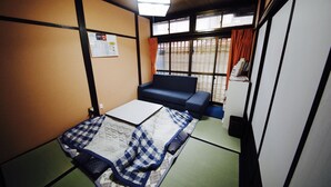 A traditional Japanese-style room with tatami flooring, a low table, a sofa, and sliding doors. - Utatei Takayama (Takayama)