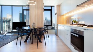 A modern kitchen with a dining area, large windows, and a city view.