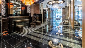 Een moderne lobby met een centraal hanglamp, marmeren vloeren en een receptiebalie.