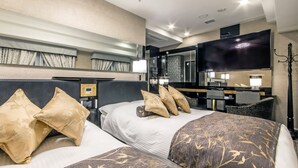 Een hotelkamer met twee bedden, een bureau, een flatscreen televisie en een badkamer in de achtergrond.