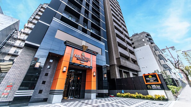 Een modern hotel met een opvallende ingang, een geruit voetpad en een bordje van een steakbar in de buurt.