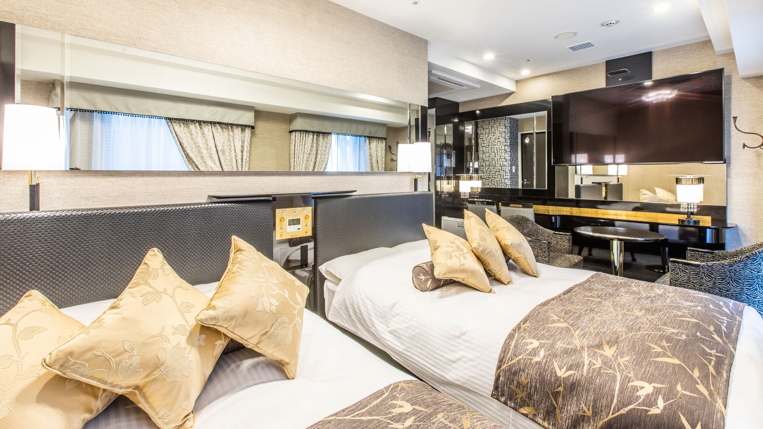 Habitación de hotel con una cama grande, un escritorio, una silla, un espejo y un televisor.