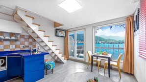Eine moderne Küche mit blauer Arbeitsplatte, einer Treppe und einem Essbereich mit Meerblick.