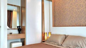 A hotel room with a bed, bedside lamps, a nightstand, a mirror, and a wall with a geometric pattern. - Amazon Residence Jomtien Pattaya By New (Pattaya)