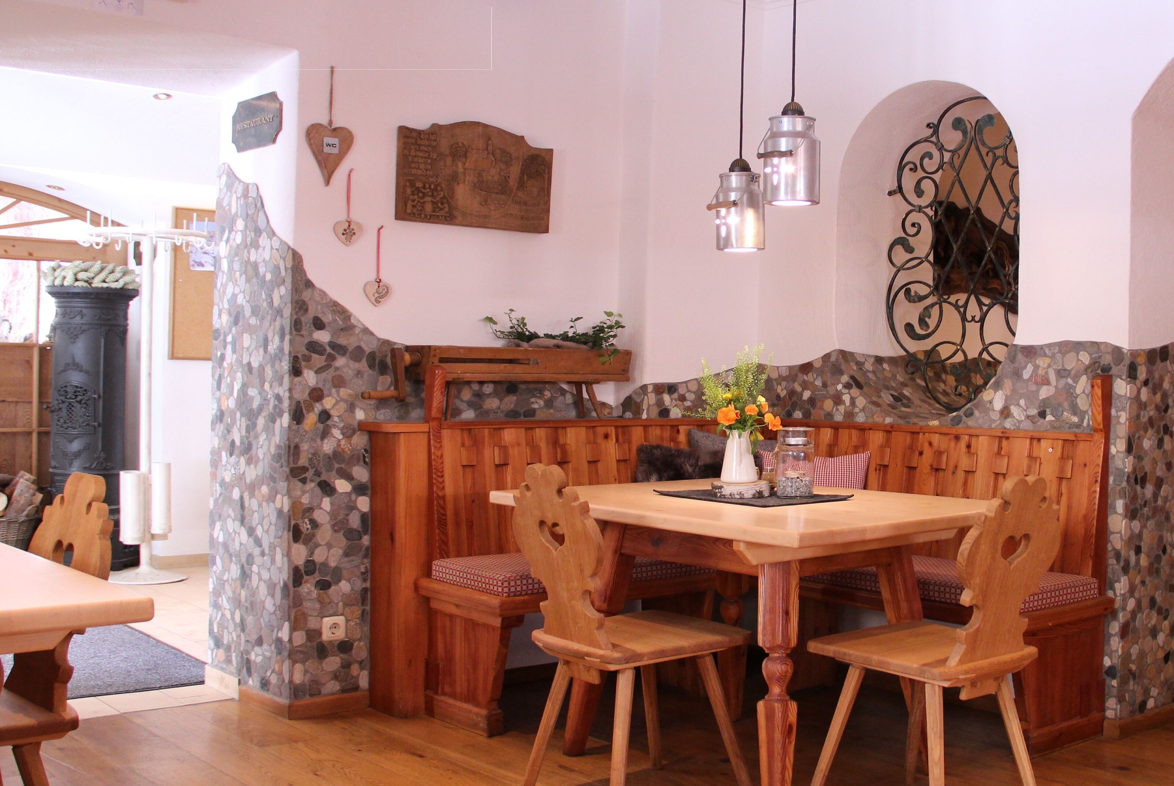 Un comedor acogedor con una pared de acento de piedra, bancos de madera y luces colgantes.