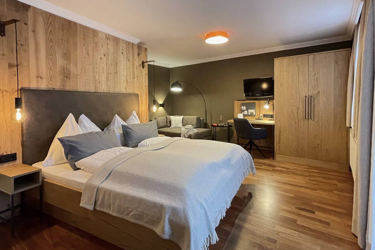 Ein Hotelzimmer mit einem großen Bett, einem Schreibtisch, einem Stuhl, einem Fernseher und einem Kleiderschrank.