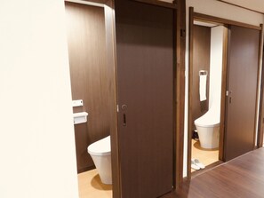 A bathroom with a wooden door, a white toilet, and a white sink.