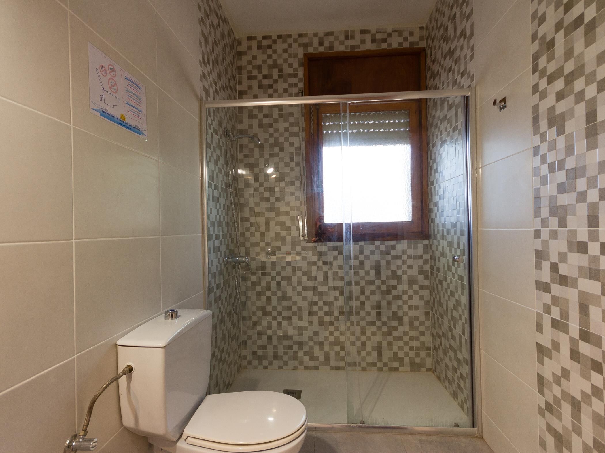 Un baño con cabina de ducha, inodoro y ventana.