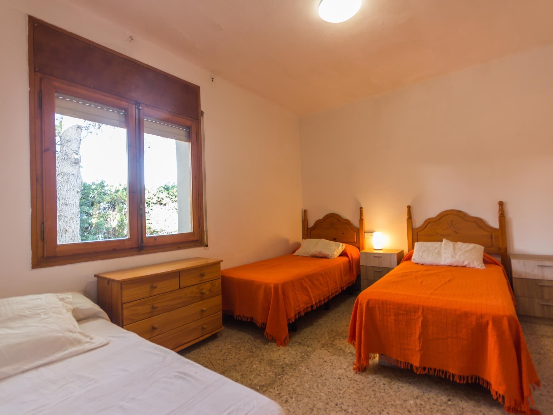A bedroom with two beds, a dresser, and a window.