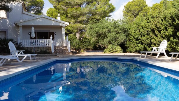 Ein Schwimmbad mit Liegestühlen und einem Haus im Hintergrund.