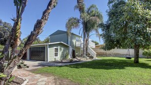 A single-story house with a garage, a front yard with a lawn, and a palm tree.