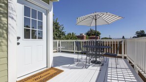 A deck with a table and chairs, a door, and a welcome mat.
