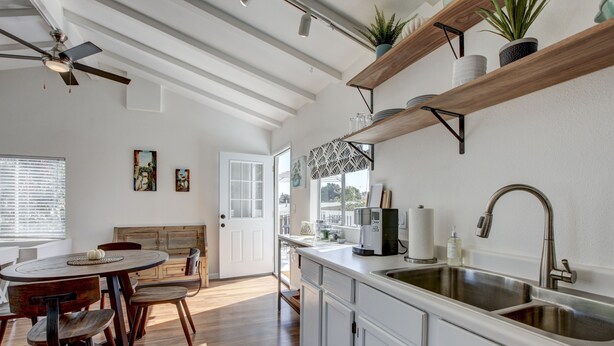 A modern kitchen with white cabinets, a wooden dining table, and a built-in sink.