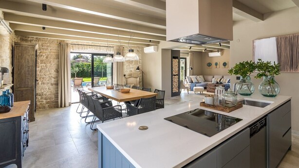Een moderne keuken met een groot eiland, een eetgedeelte en een stenen muur.