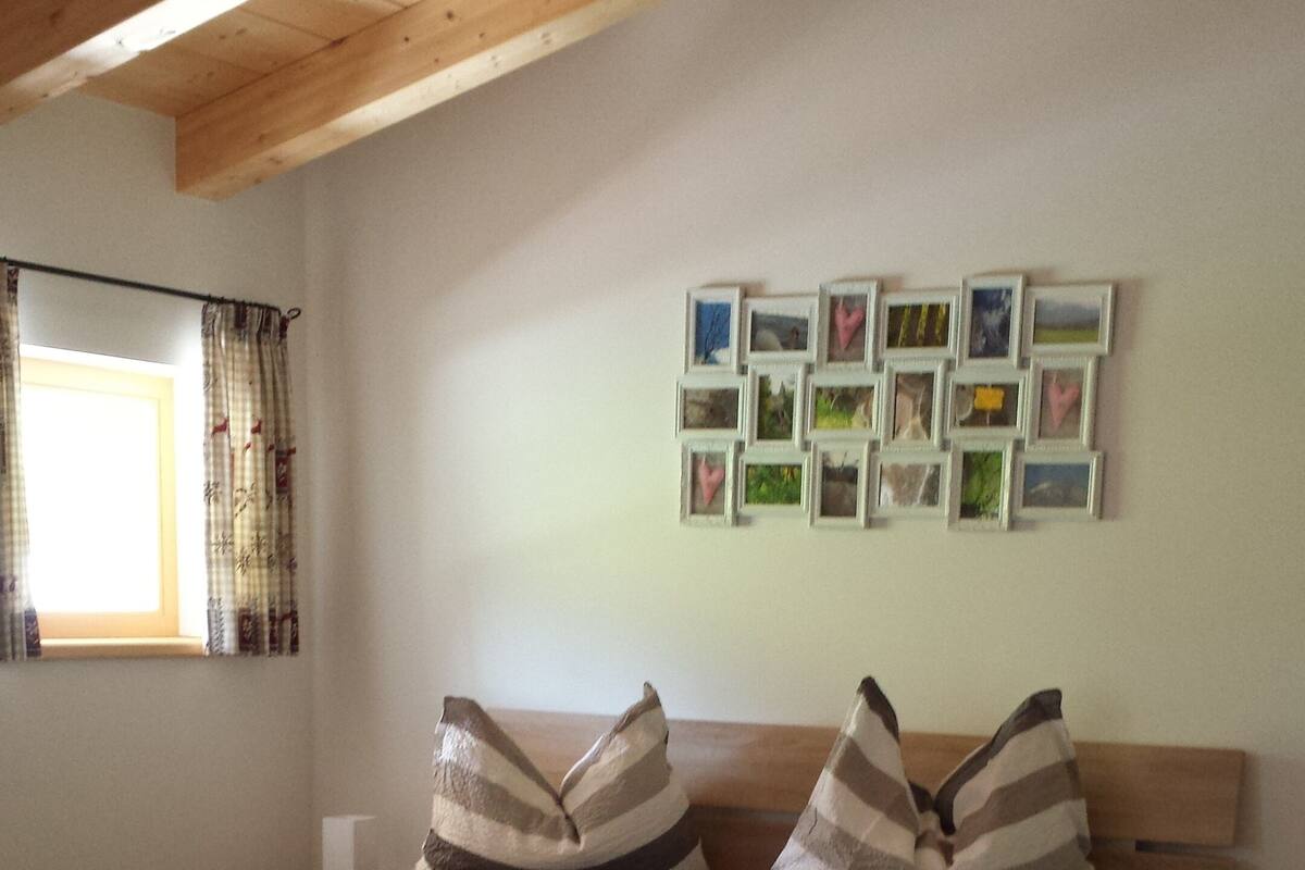 A bedroom with a wooden bed, striped pillows, a nightstand, and a wall with framed pictures.