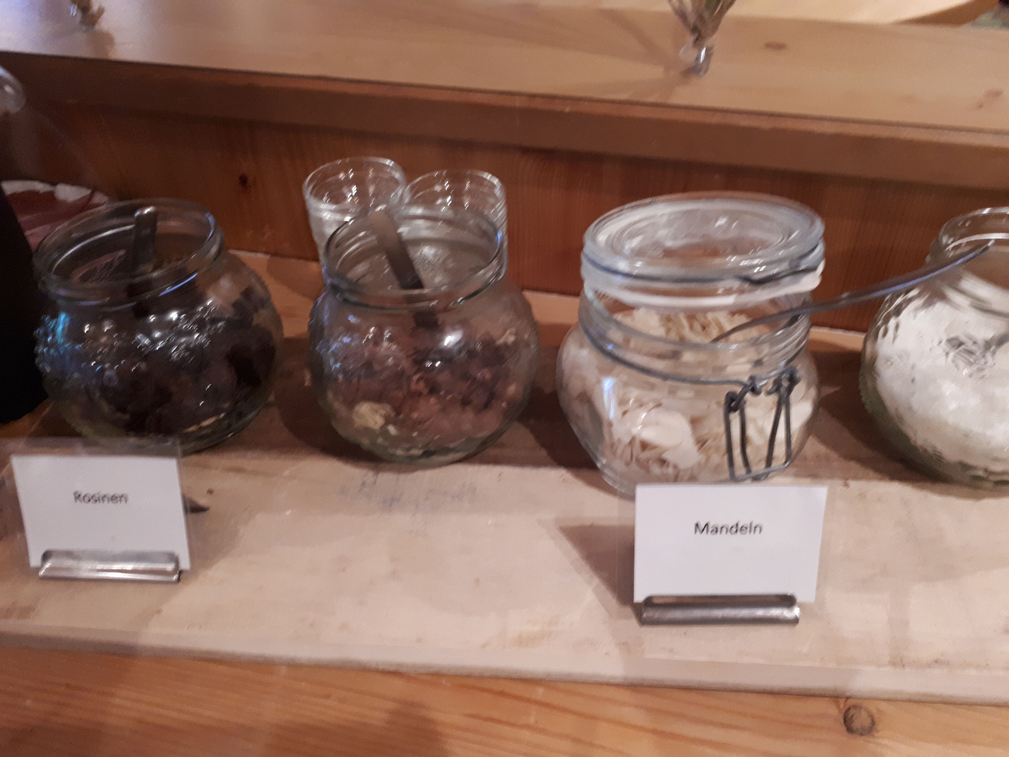 A display of food items in glass jars with labels 'Rosinen' and 'Mandeln'.