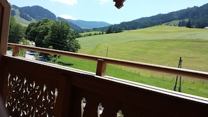 Ein Balkon mit Blick auf ein grünes Feld und ferne Berge.