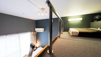 Habitación de hotel con una cama, un escritorio, una silla, un ventilador y una ventana con cortinas.