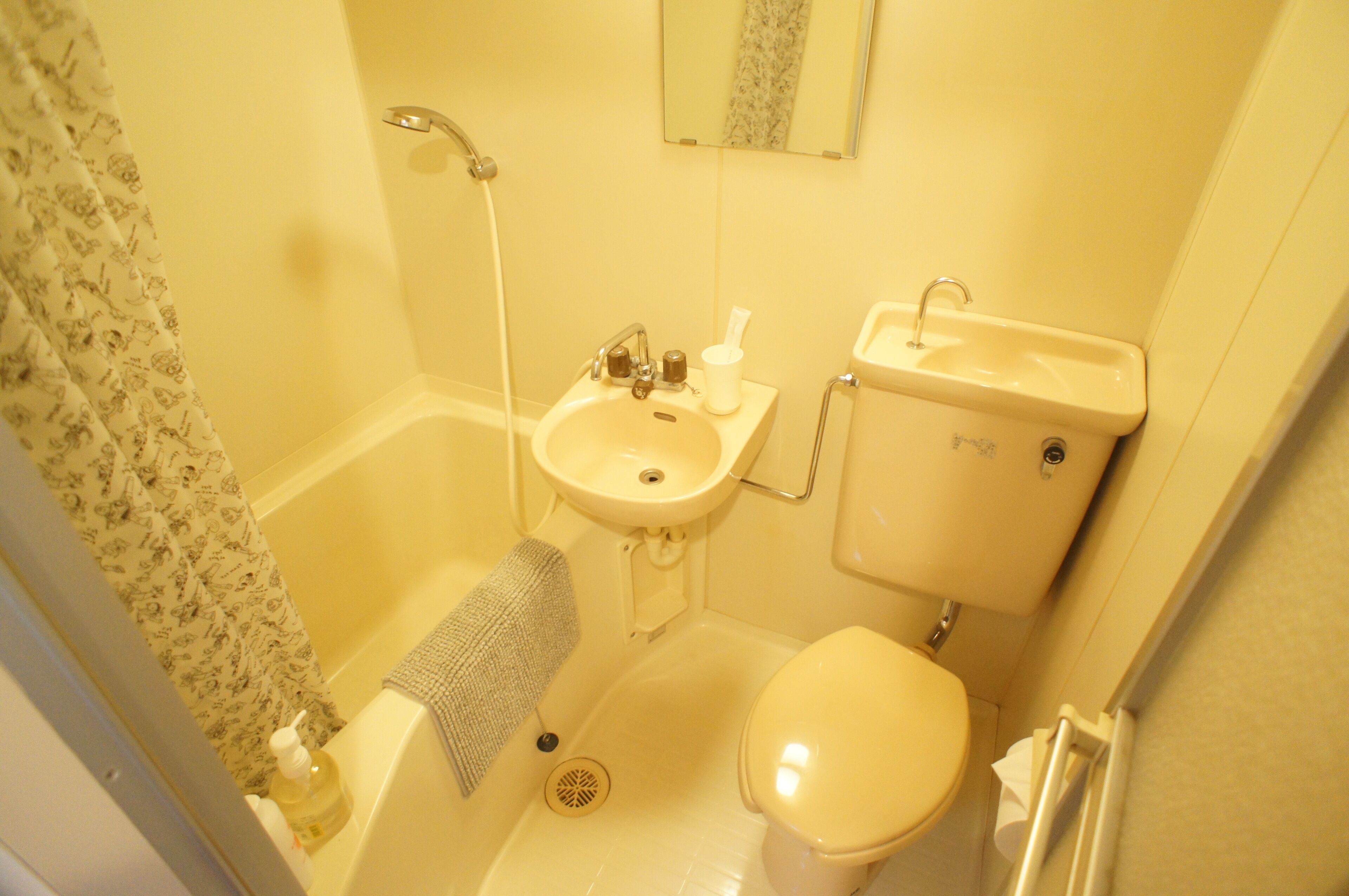 A small bathroom with a bathtub, sink, toilet, and a showerhead.