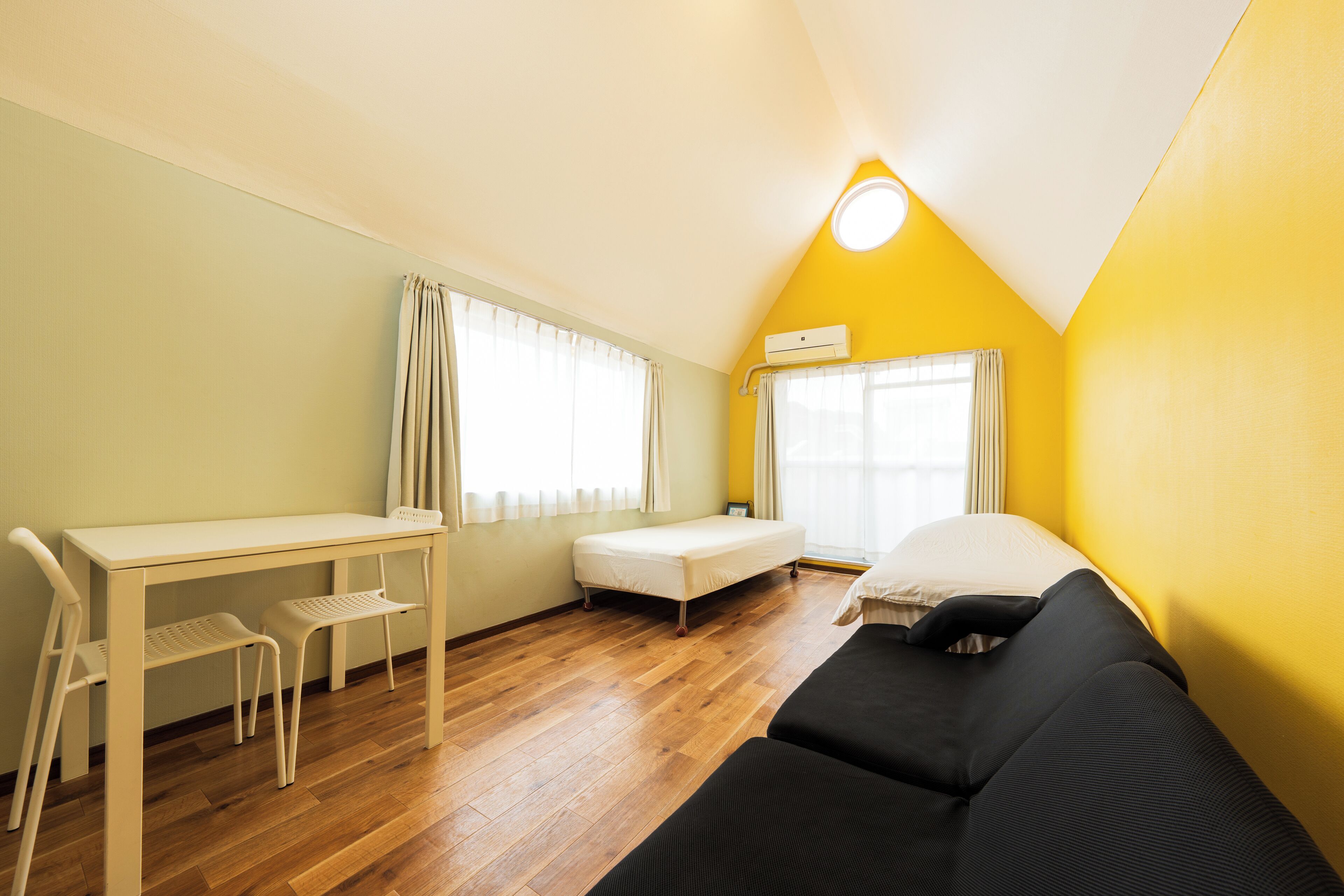 A compact room with a bed, a desk, and two chairs.