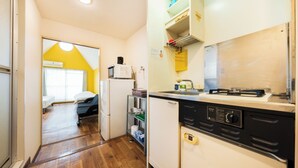 Een compacte keuken met een magnetron, koelkast en vaatwasser. Door een open deur is een klein eethoekje met een tafel en stoelen zichtbaar.