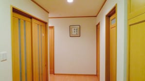 A narrow hallway with wooden doors and a framed picture on the wall. - Utatei Villa (Takayama)