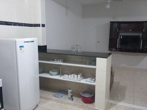 Kitchen area with refrigerator, sink, and storage shelves.