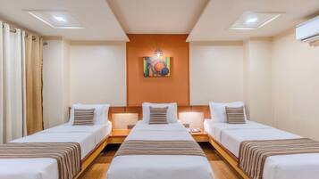 A hotel room with two single beds, a large bed, and a wall-mounted artwork.