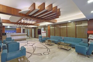 Un vestíbulo de hotel con sofás azules, un mostrador de recepción y un diseño de techo moderno.