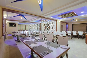 A modern dining area with long tables, chairs, and a decorative ceiling.